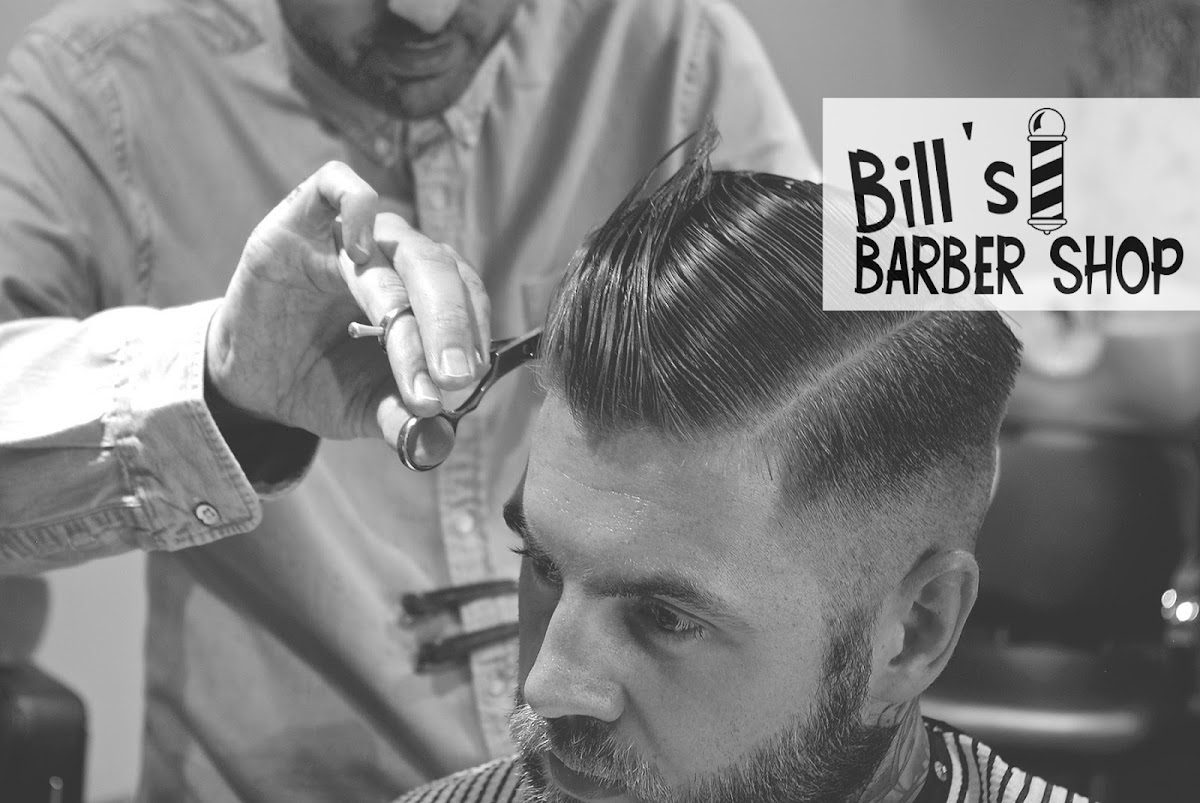A barber at Bill's Barbers scissor-cutting a customer's hair