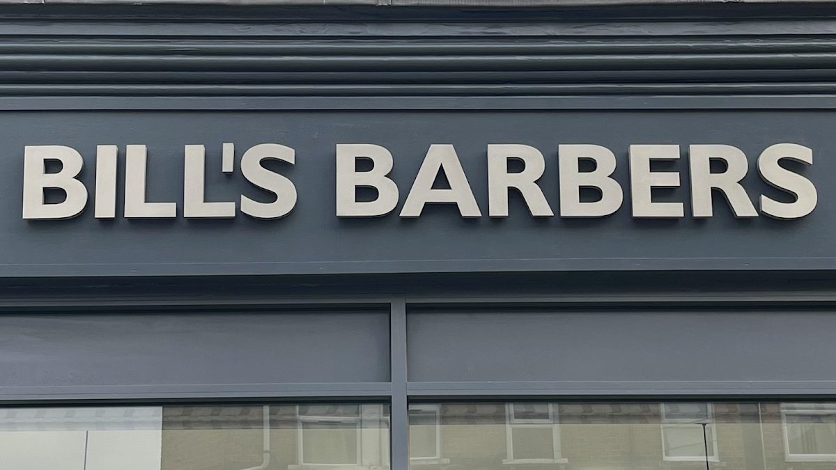 The silver BILL'S BARBERS lettering above the shop